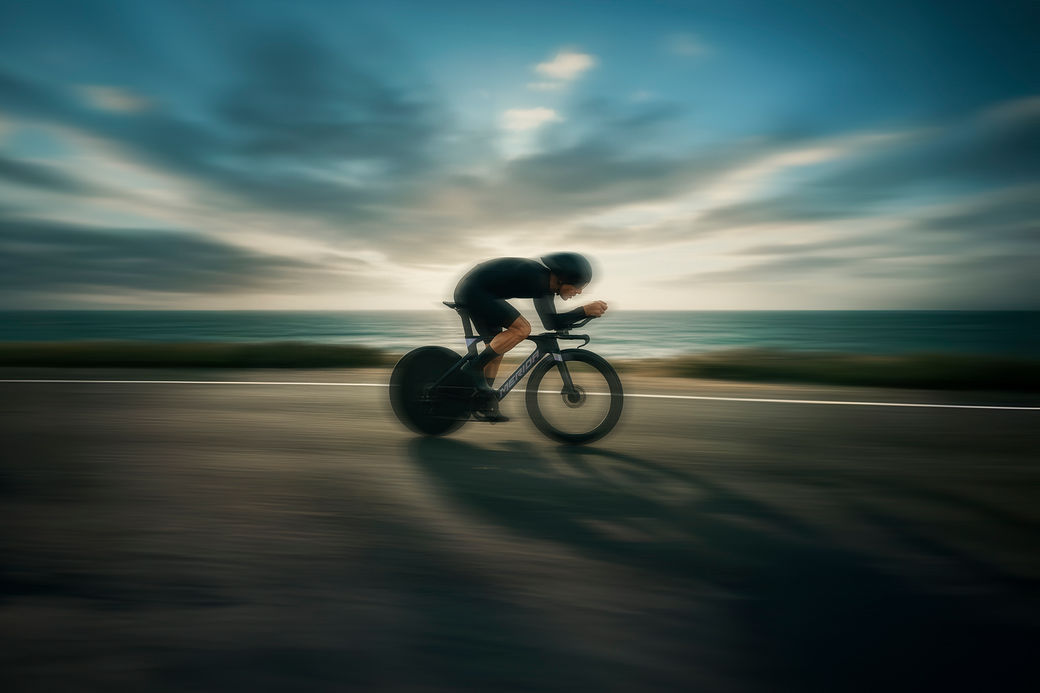 Triathlet in Aeroposition auf einer Küstenstraße
